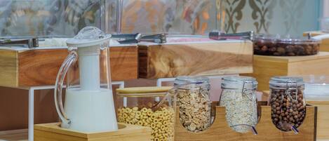 A buffet setup with various food items in containers, including cereals and nuts, arranged on wooden stands.