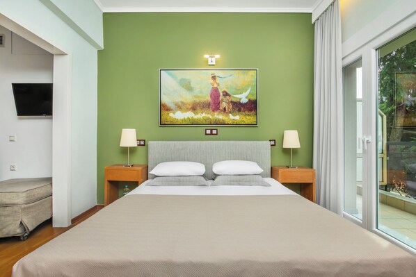 Habitación de hotel con cama, dos mesitas de noche con lámparas, un cuadro en la pared y televisor en la pared.