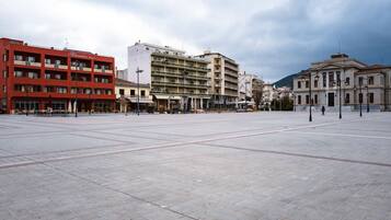 A spacious public square with a red building labeled "Kumelion" on the left, a multi-story building in the center, and a classical building on the right.