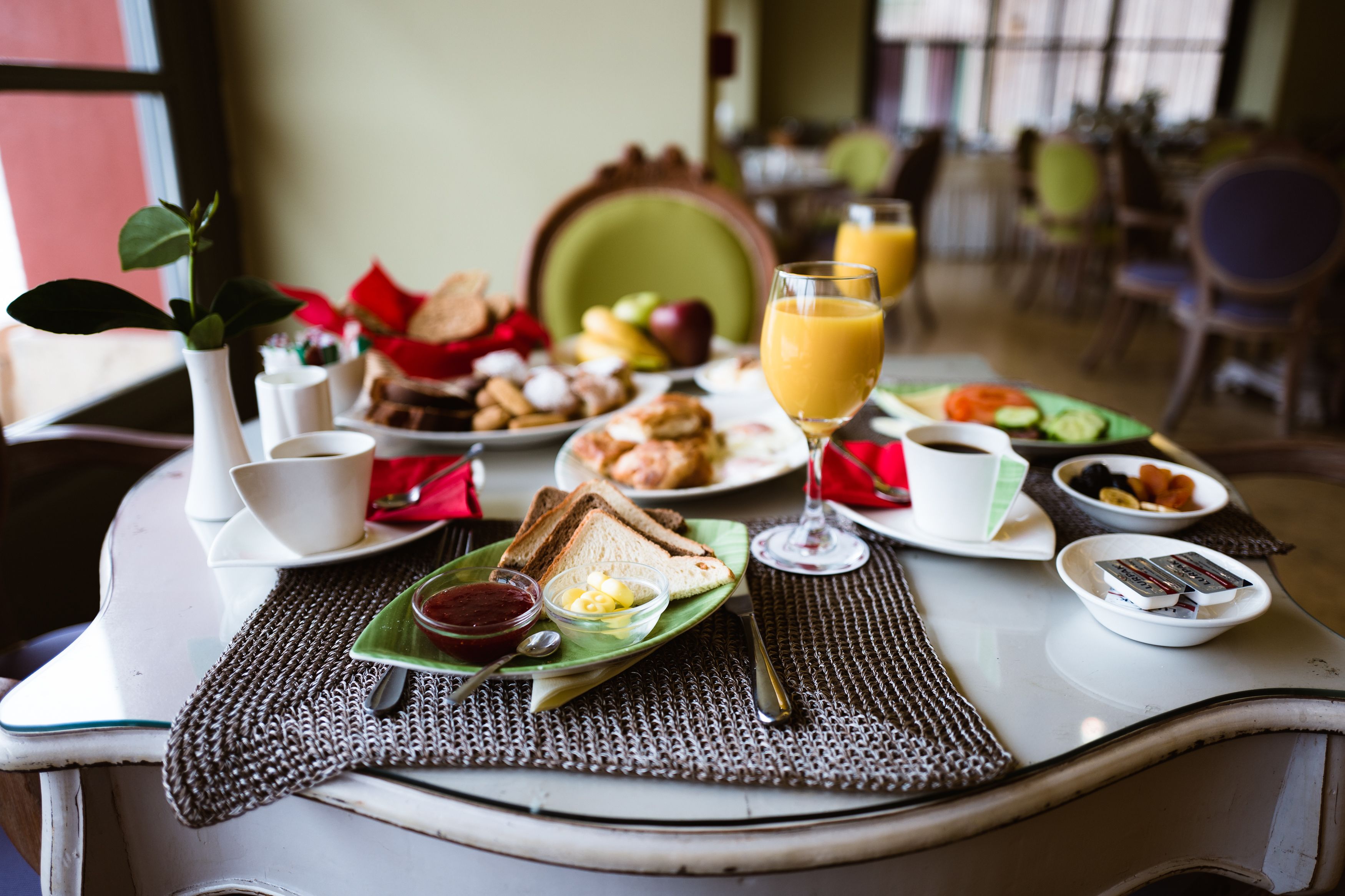 Un desayuno con diversos alimentos, como tostadas, huevos y fruta, sobre una mesa con un posavasos.