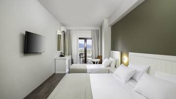 A hotel room with two beds, a TV, a desk, and a view of the outdoors.