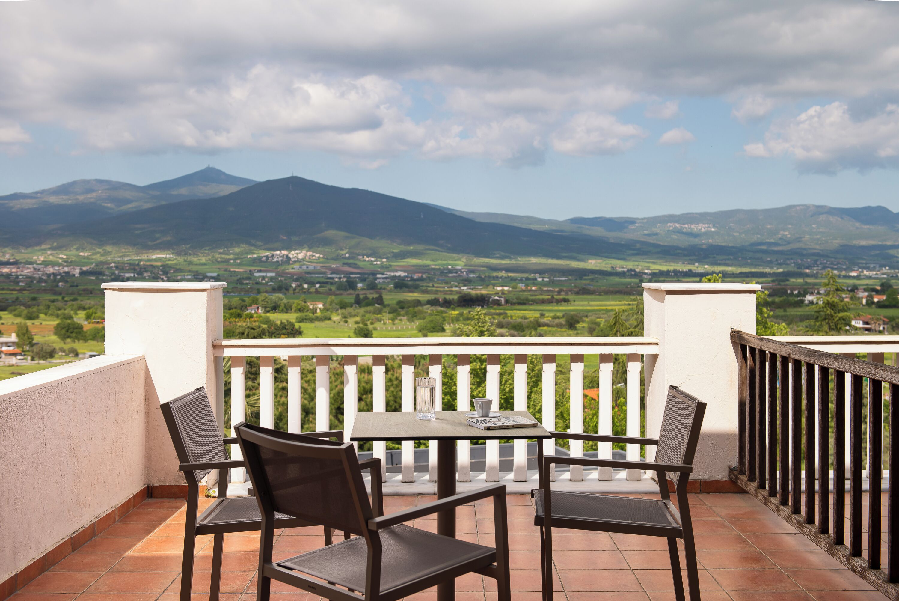 Un balcón con dos sillas y una mesa, con vistas a un paisaje montañoso.