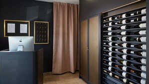 A modern reception area with a desk, framed certificates, and a wine rack.