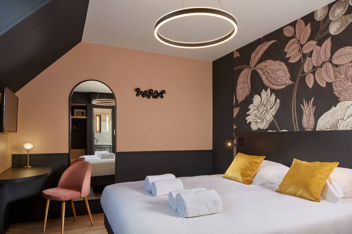 Une chambre d’hôtel moderne équipée d’un grand lit, d’un bureau, d’une chaise et d’un miroir.