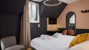 A modern hotel room with a large bed, a chair, a desk, and a mirror.