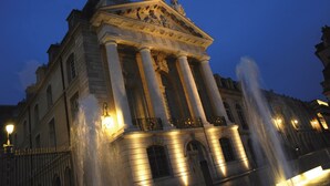 Un edificio clásico con columnas y estatuas, iluminado con luz artificial.