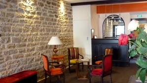Un vestíbulo con paredes de piedra, muebles de madera y una recepción con espejo.