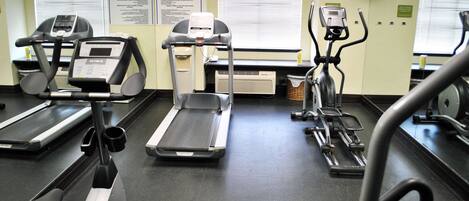 Un gimnasio con cintas de correr, elípticas y bicicletas estáticas.