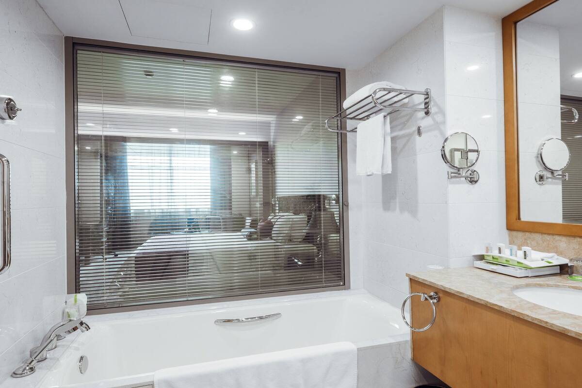 A modern bathroom with a large mirror, a bathtub, a sink, and a shower.