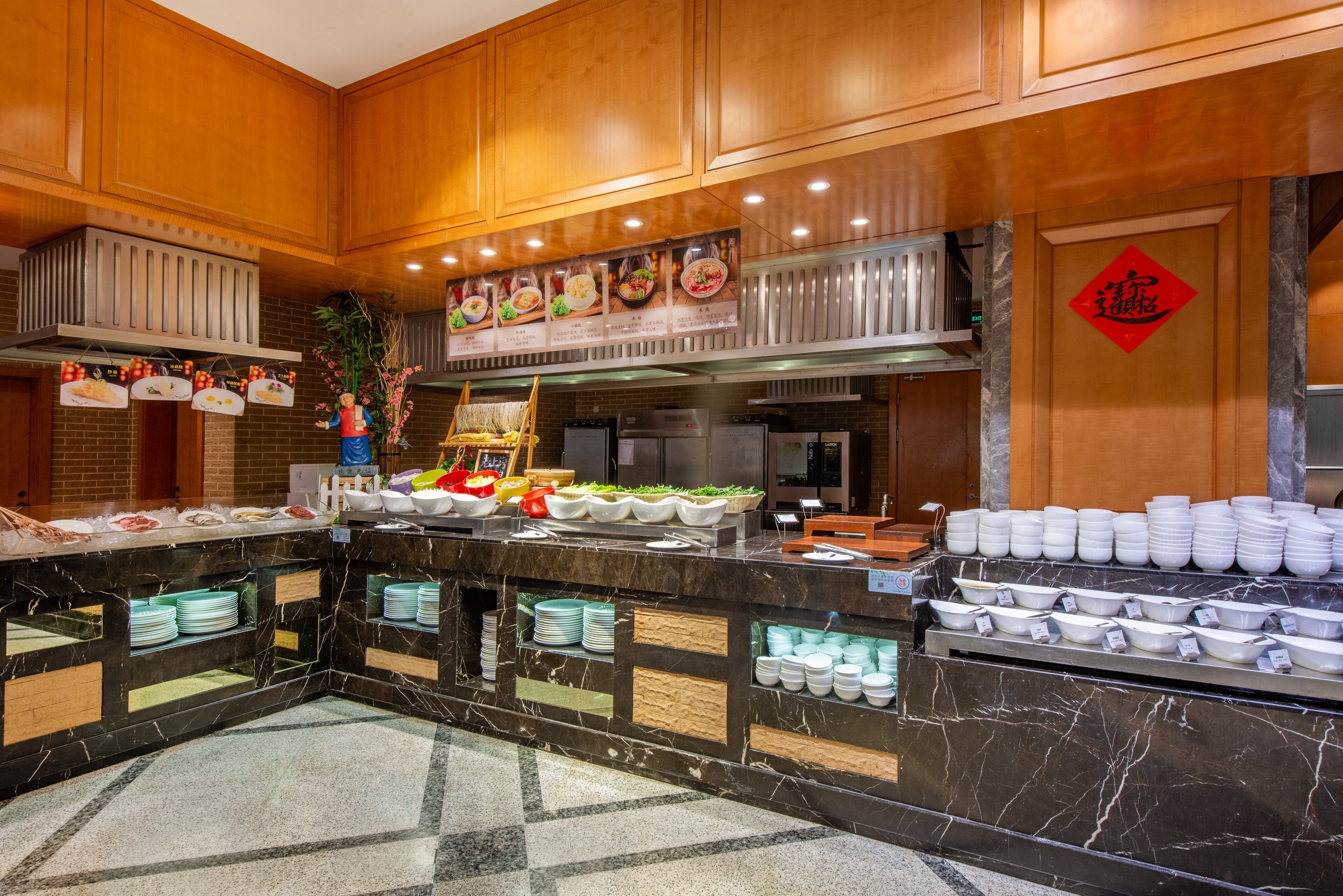 Una cocina de hotel con encimeras de mármol, una disposición tipo bufé y un letrero con un carácter chino rojo.