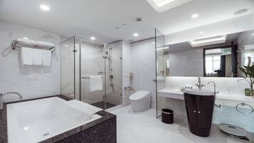 A modern bathroom with a glass-enclosed shower, a freestanding bathtub, a vanity with a sink, and a toilet.