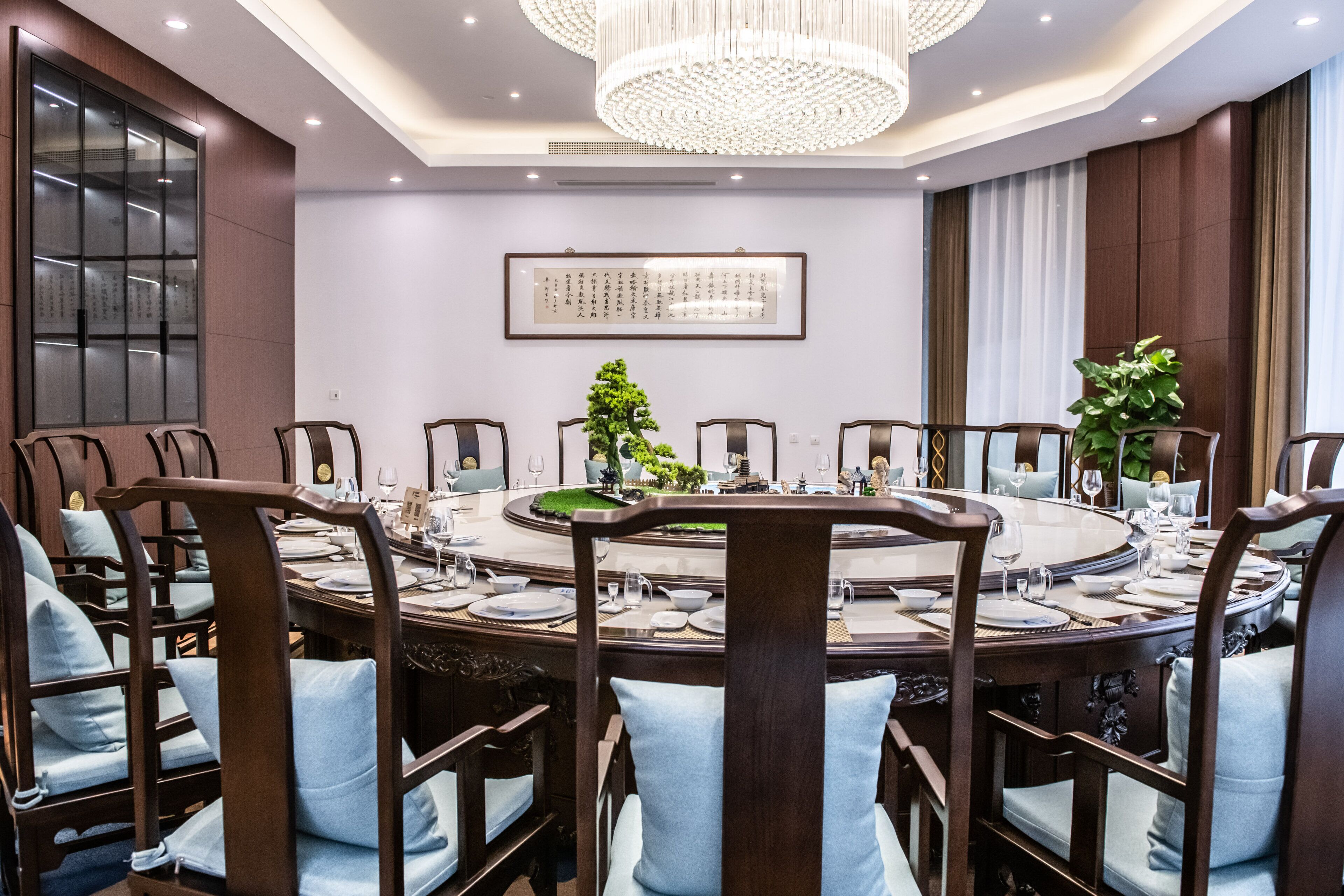 A conference room with a round table, chairs, and a chandelier.