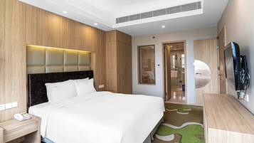 Camera d'albergo con un letto, una scrivania, un telefono, una televisione e un bagno visibile tramite una porta in vetro.