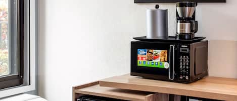 Una kitchenette compacta con cafetera, refrigerador pequeño y microondas.