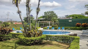 A pool area with lounge chairs, a covered seating area, and a sign indicating no diving.