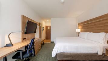 Habitación de hotel con cama, escritorio, silla, televisión y cabecera de madera.