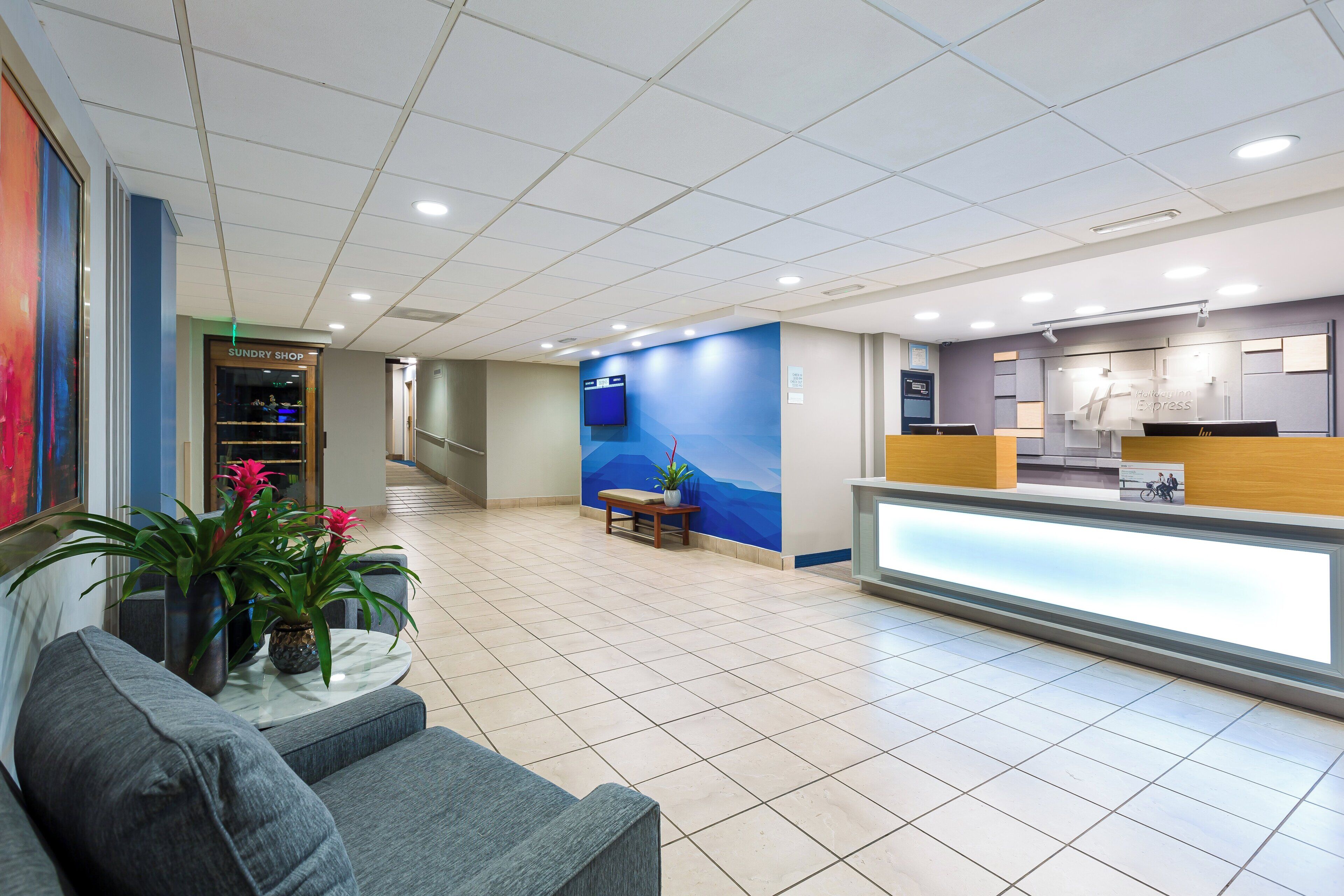 A hotel lobby with a reception desk, seating area, and a Sundry Shop.