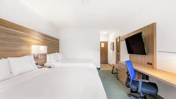 A hotel room with two beds, a desk with a chair, a flat-screen TV, and a wooden headboard.