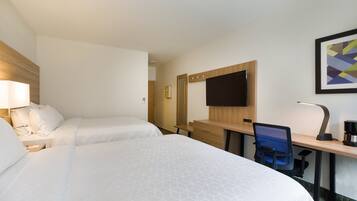 Een hotelkamer met twee bedden, een bureau, een stoel, een televisie en een koffiezetapparaat.