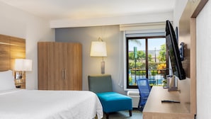 A hotel room with a bed, a desk with a computer, a TV, a chair, and a window with a view of the outdoors. - Holiday Inn Express San Jose Costa Rica Airport by IHG (Rio Segundo)