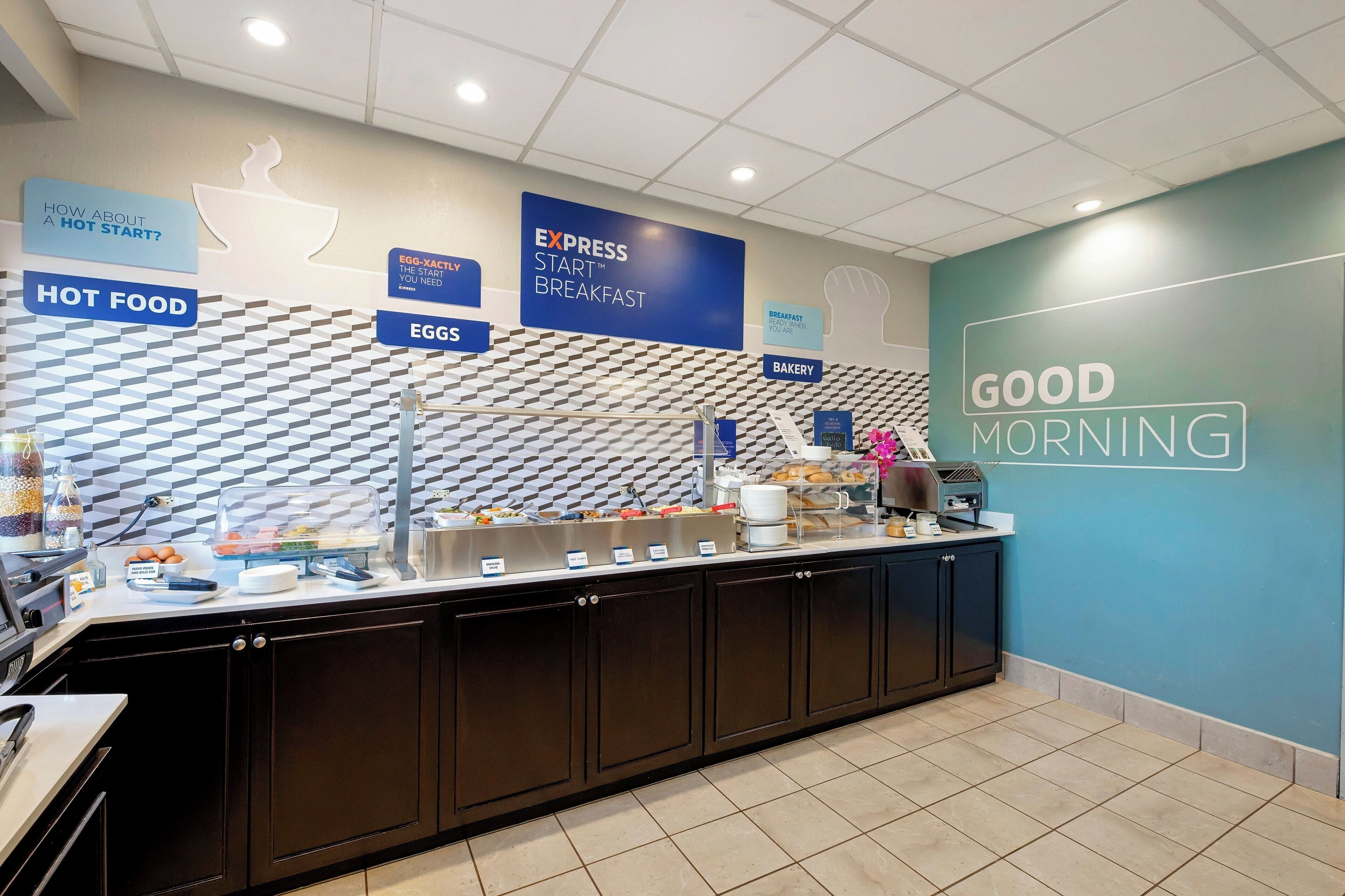A breakfast buffet area with labeled sections for hot food, eggs, and bakery items.