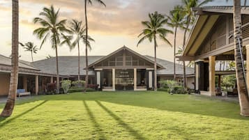 A resort with a central building, palm trees, and a well-maintained lawn.