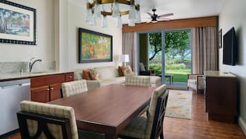 A modern kitchen with a dining area, a large painting, and a view of the outdoors.