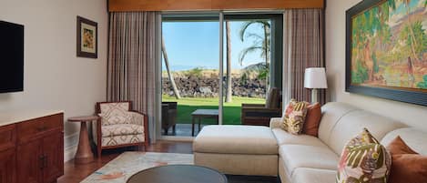 A hotel room with a sofa, armchair, and a dining table.