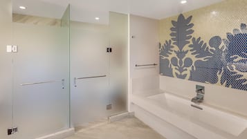 Une salle de bain moderne avec une douche à l’italienne en verre, une baignoire blanche et un mur décoratif orné de motifs de feuilles.