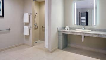 Un baño moderno con ducha, lavamanos y espejo.