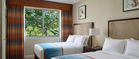 A hotel room with two beds, a window with curtains, a nightstand with a lamp, and a framed picture on the wall.