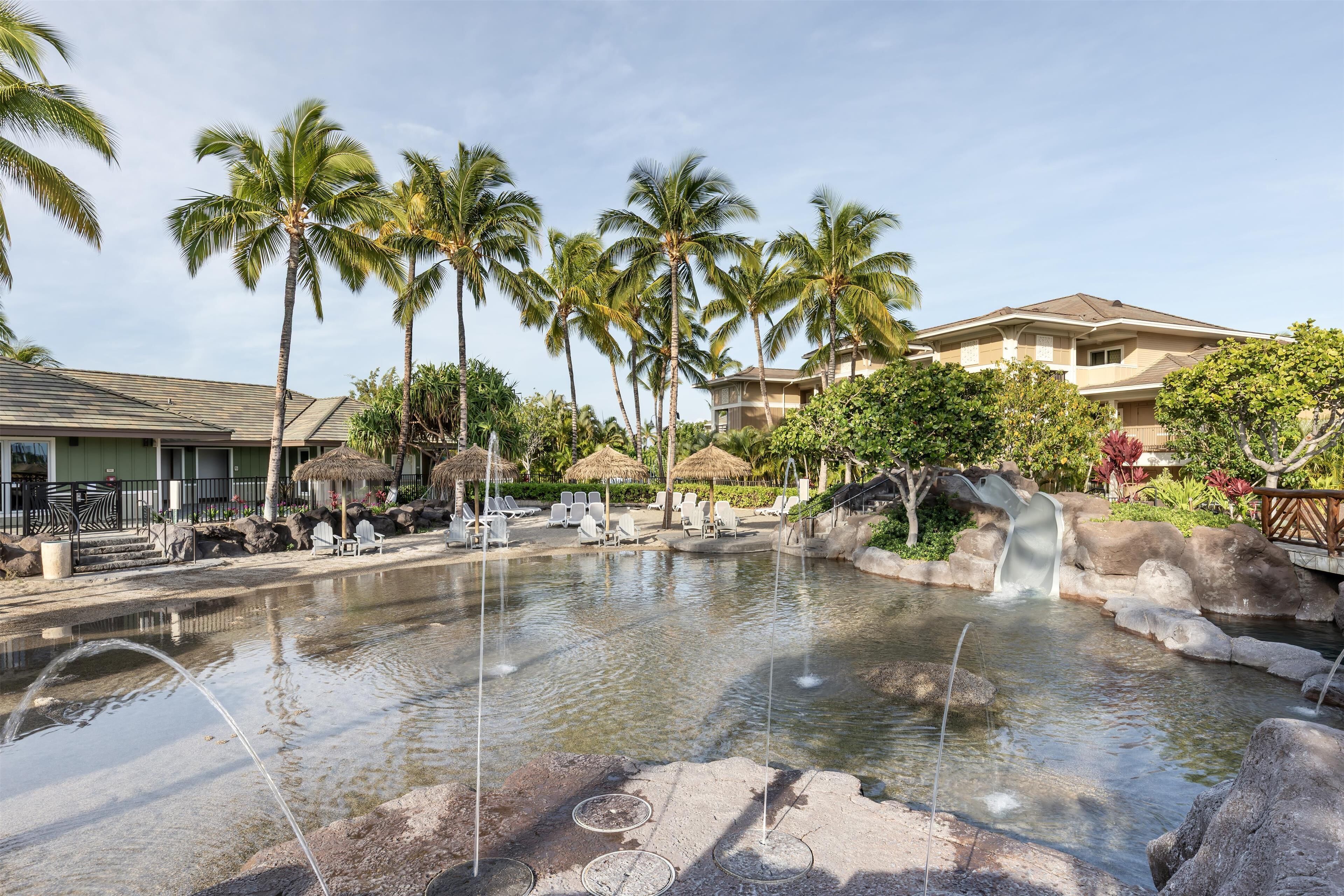 Piscina de resort com palmeiras, espreguiçadeiras e uma cascata.