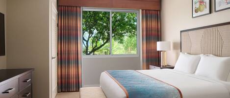 Una habitación de hotel con cama, escritorio, silla, ventana con cortinas y lámpara.