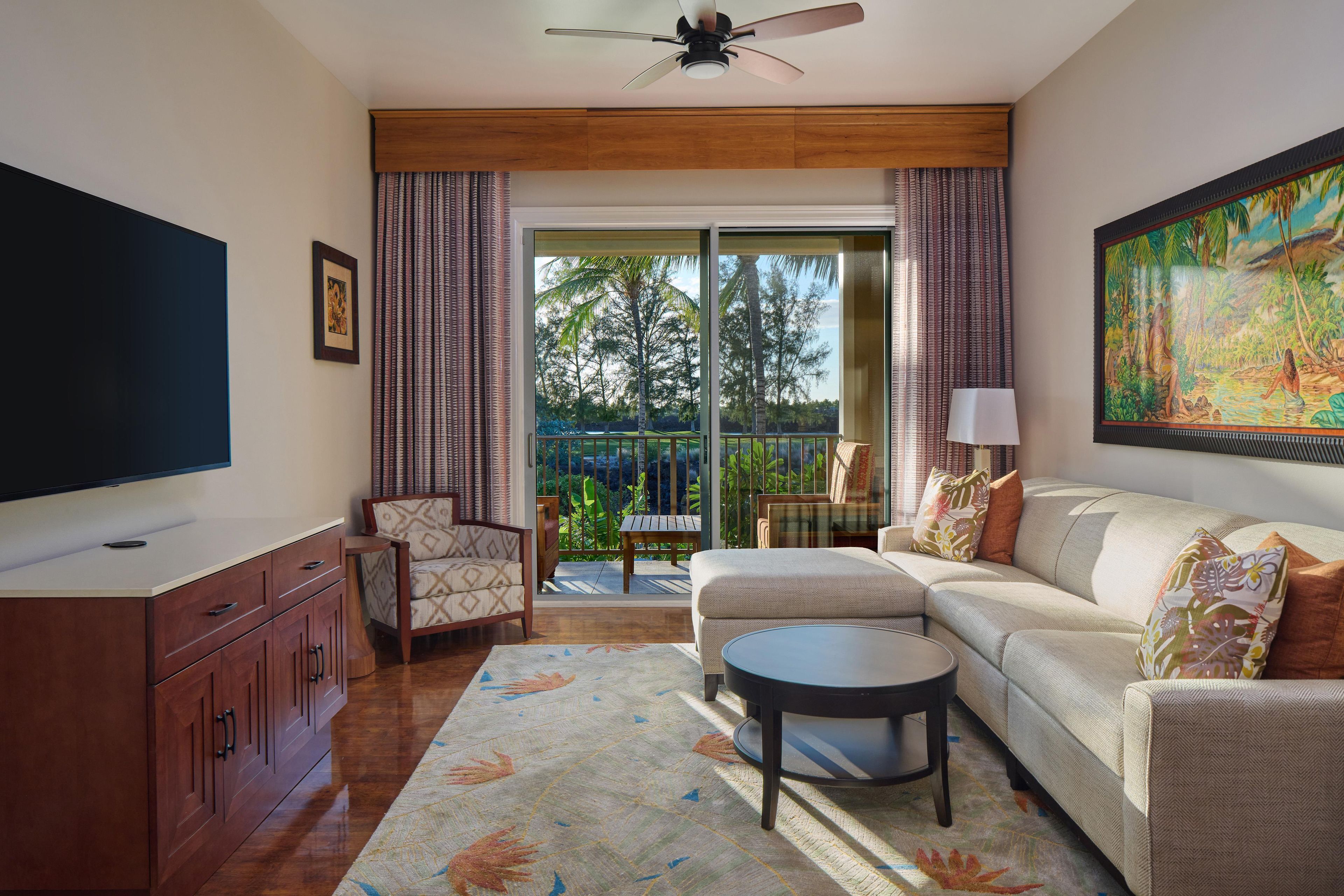 A living room with a flat-screen TV, a sofa, a chair, a coffee table, and a painting.