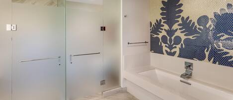 Un baño moderno con cabina de ducha de vidrio, una bañera blanca y azulejos decorativos en la pared.