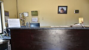 A reception desk with a computer, a framed picture on the wall, and a clock.