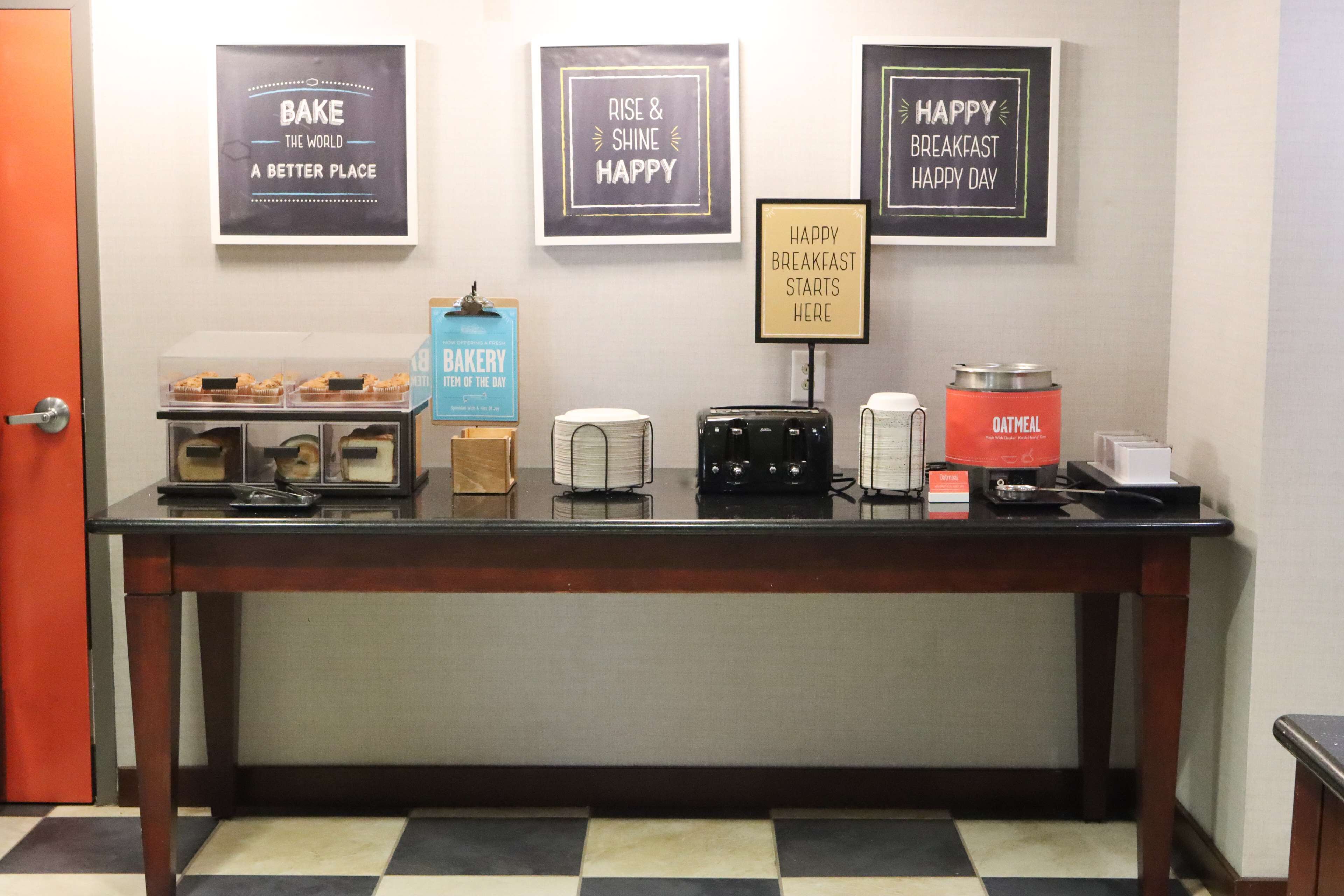A breakfast bar with a coffee machine, toaster, and a sign that says "Happy Breakfast Starts Here".