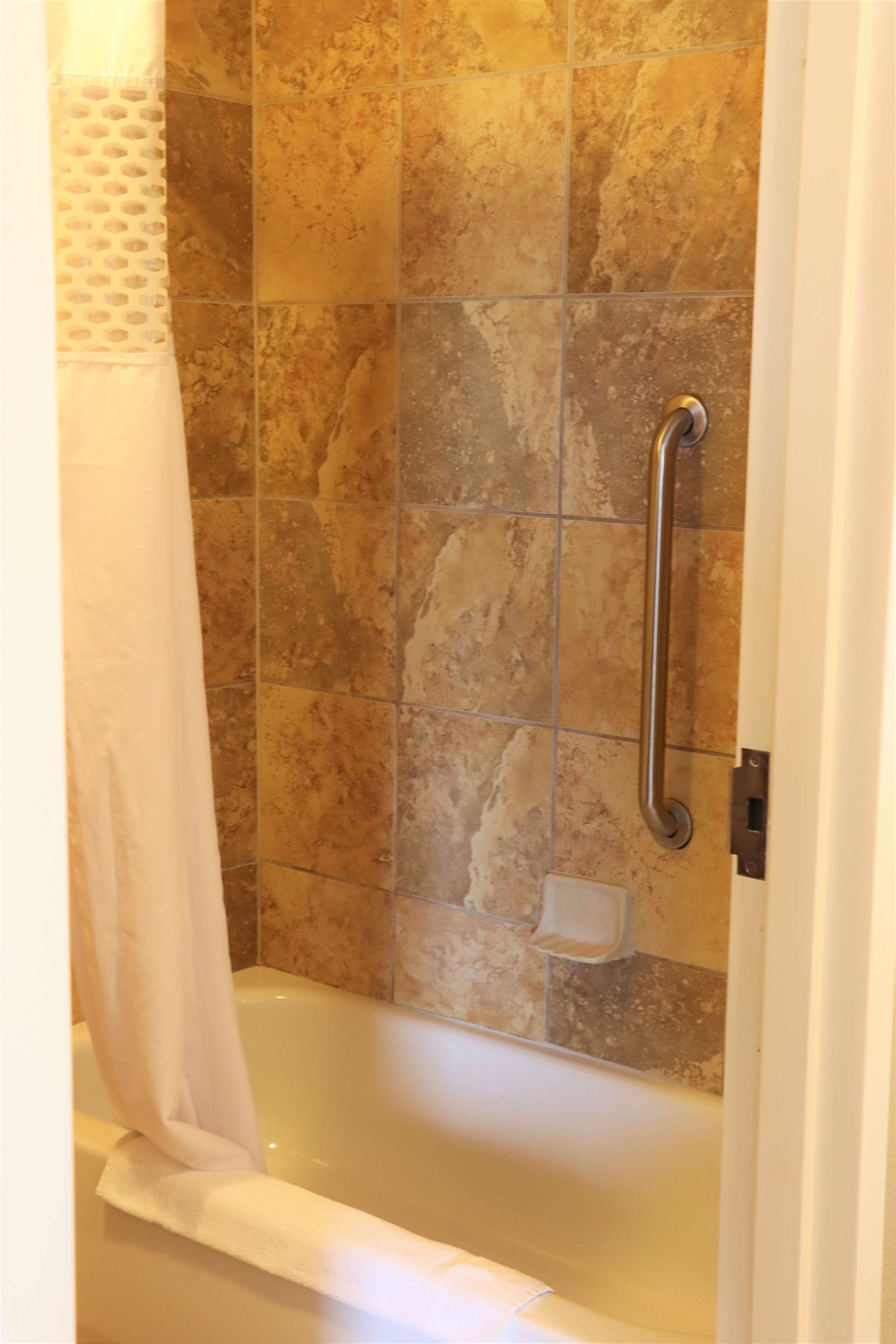 Ein Badezimmer mit einer Badewanne, einer Dusche mit Haltegriff und einem Handtuchhalter.