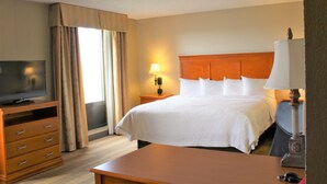 A hotel room with a bed, a TV, a desk, and a lamp.