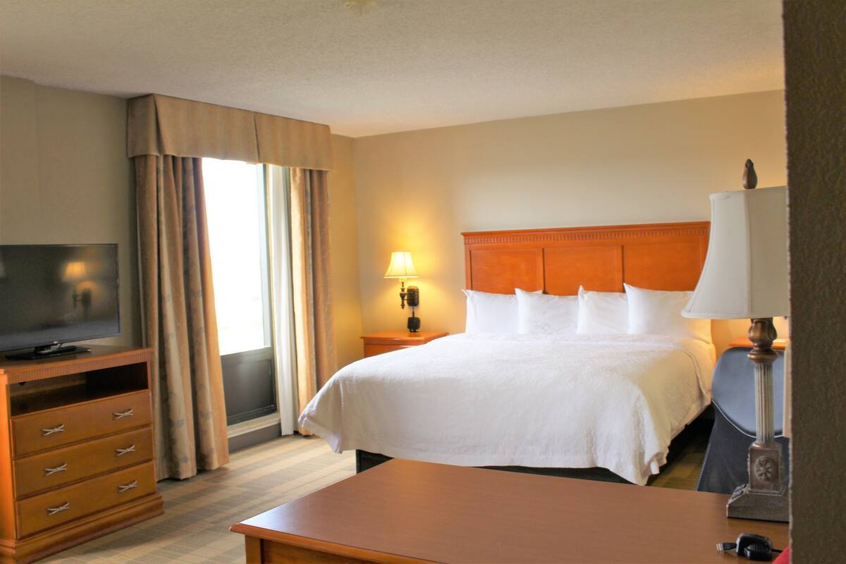 A hotel room with a bed, a TV, a desk, and a lamp.