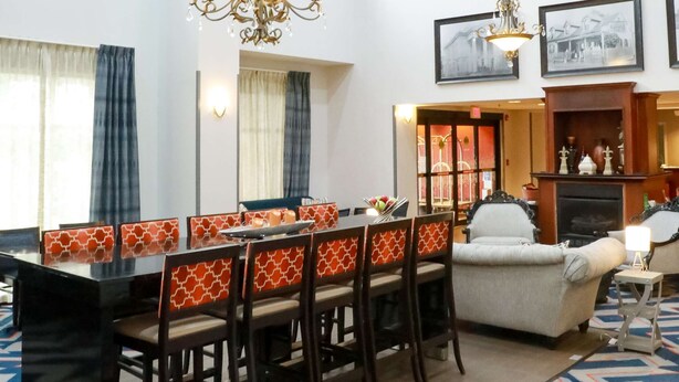 A hotel lobby with a dining area, a fireplace, and a chandelier.