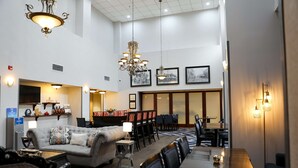 A hotel lobby with a seating area, a dining table, and a chandelier.