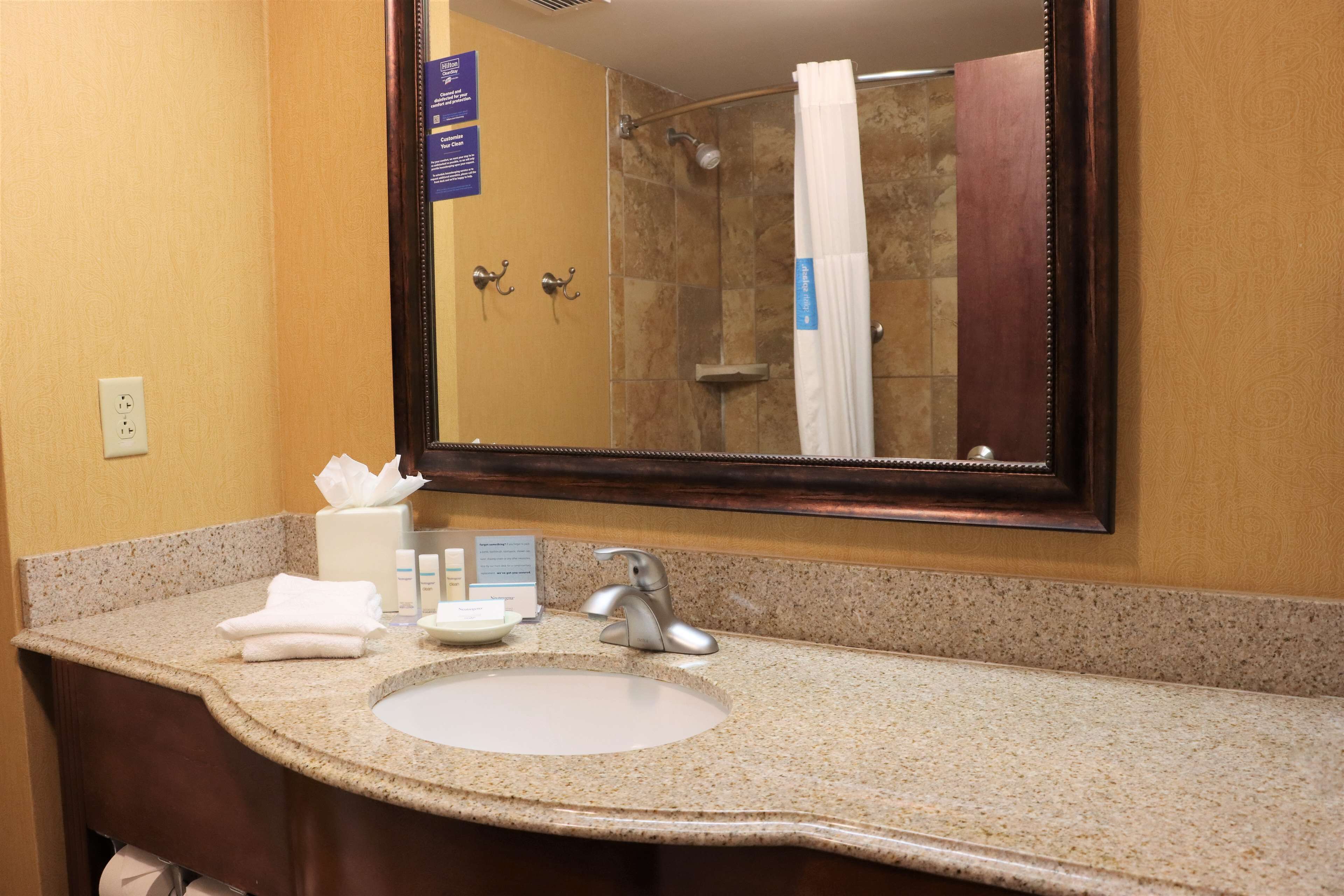 A bathroom with a granite countertop, a sink, a mirror, and a shower area visible in the reflection.