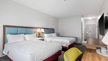 Quarto de hotel com duas camas, uma escrivaninha, uma cadeira e uma televisão.