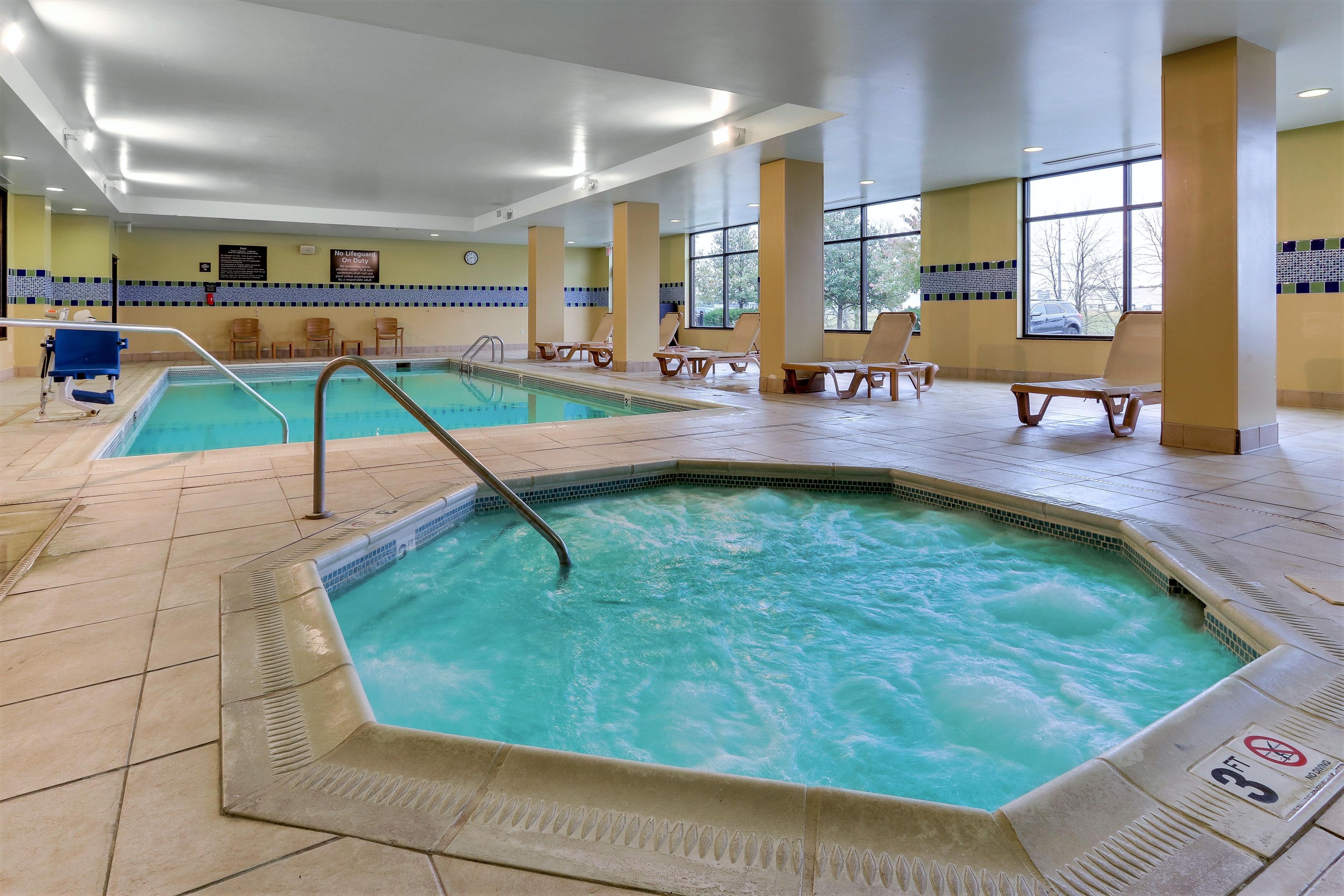 Piscina interior com várias pistas de natação, cadeiras de descanso e placa de salva-vidas.