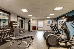 A gym with treadmills, dumbbells, and weight machines.