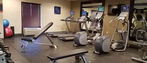 A gym with treadmills, elliptical machines, and free weights.