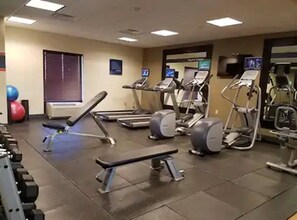 Un gimnasio con cintas de correr, elípticas y pesas sueltas.
