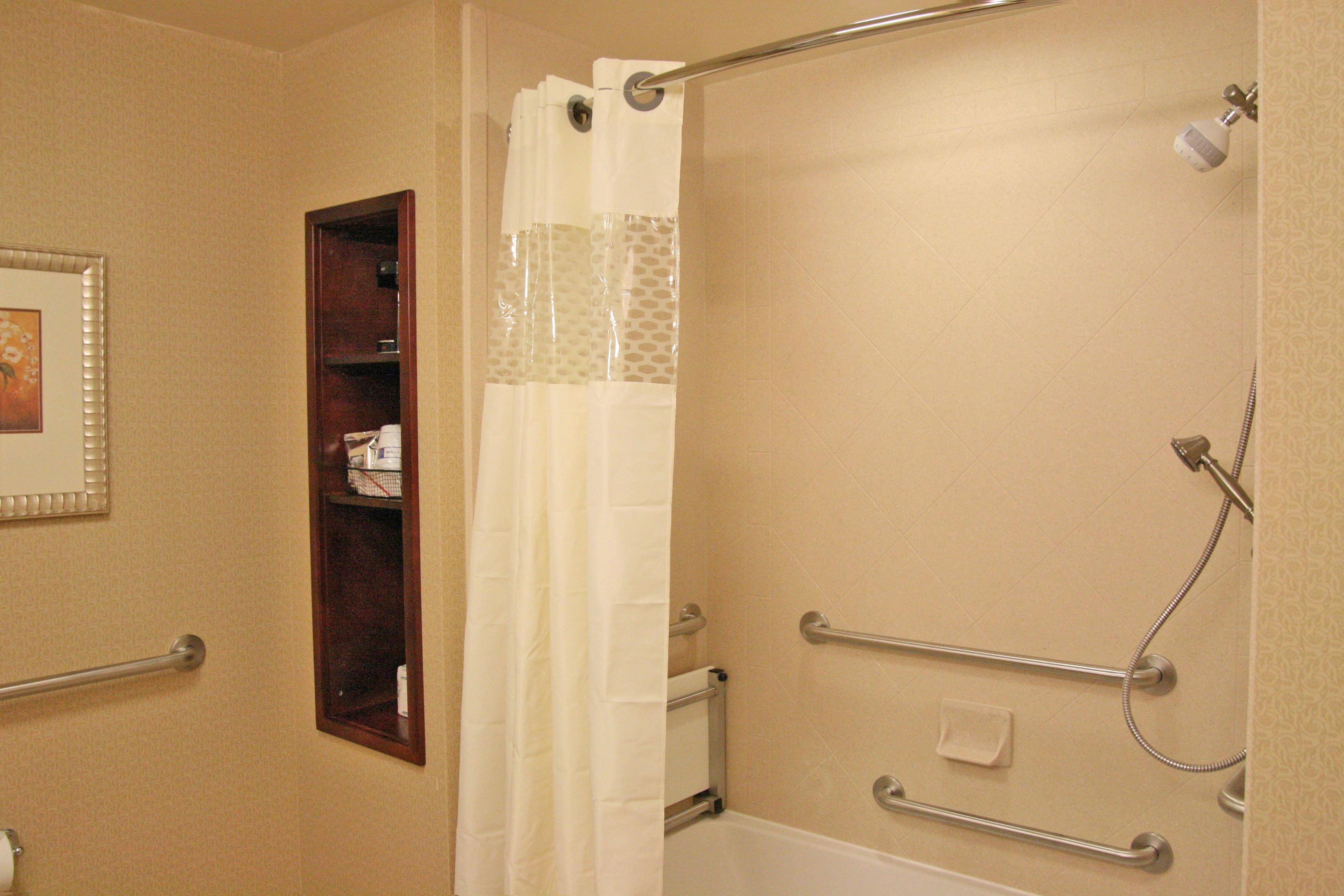 A bathroom with a shower, a towel rack, and a shelf with toiletries.