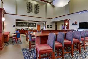 A hotel lobby with a bar area, seating, and a television. - Hampton Inn & Suites Indianapolis-Airport (Indianapolis)